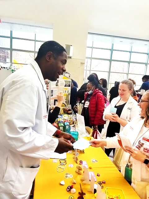 A candid image of pharmacist Charrai Byrd interacting with other healthcare professionals. He is holding a brochure and talking from behind a table.