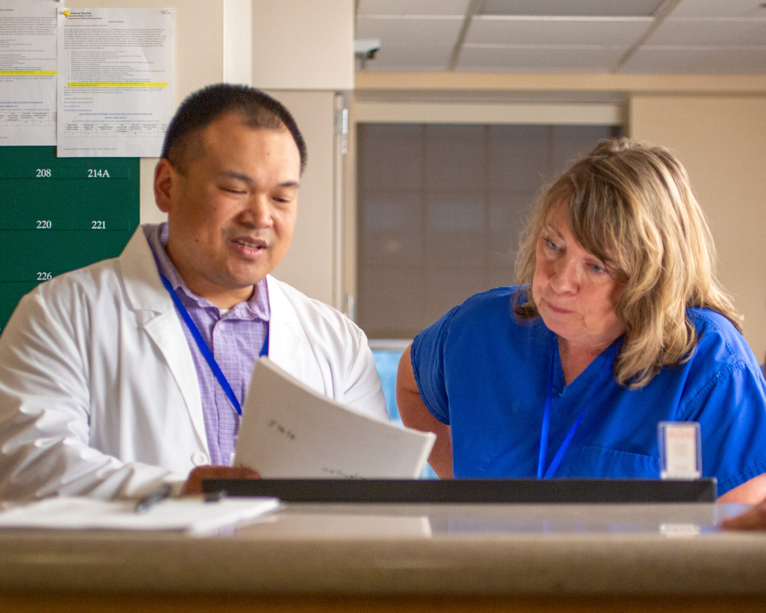 A health-system pharmacist and a health care professional reviewing a set of documents together.