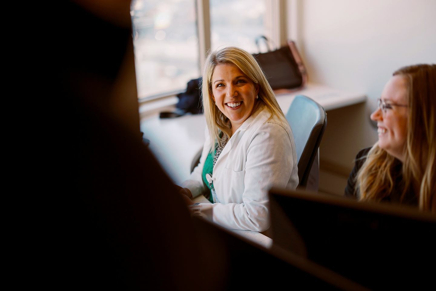 An image of pharmacist Olivia Morgan smiling from behind her desk. She is seated and is wearing a white lab coat.