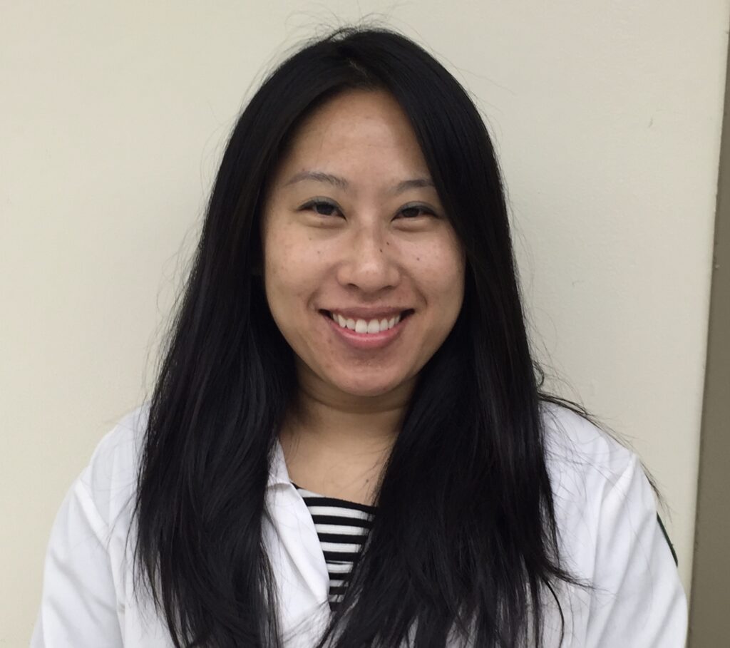 Pharmacist Yujing Steenwyk is smiling - blue blouse with a hospital badge.