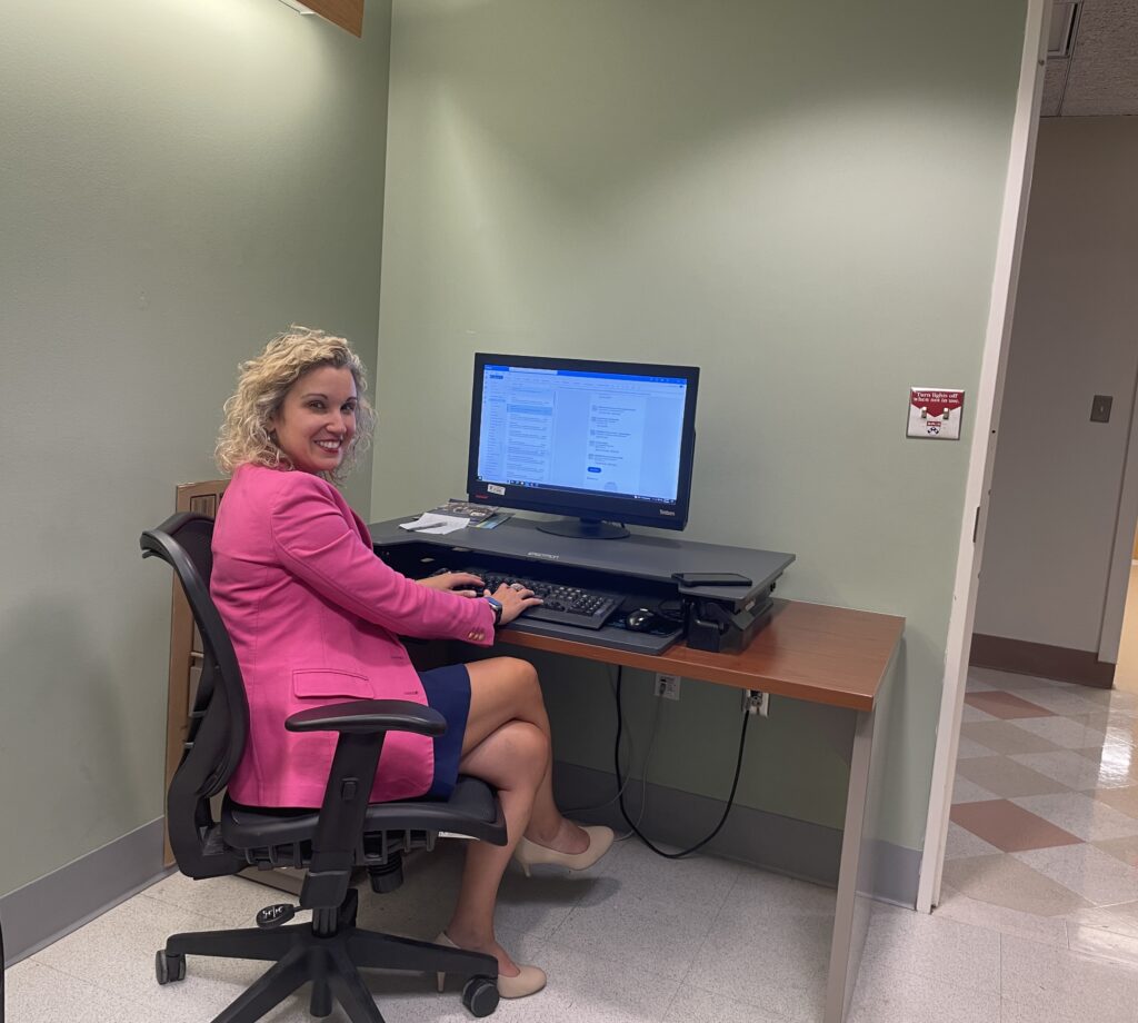 Tanya Uritsky is sitting at her computer, smiling at the camera over her shoulder.