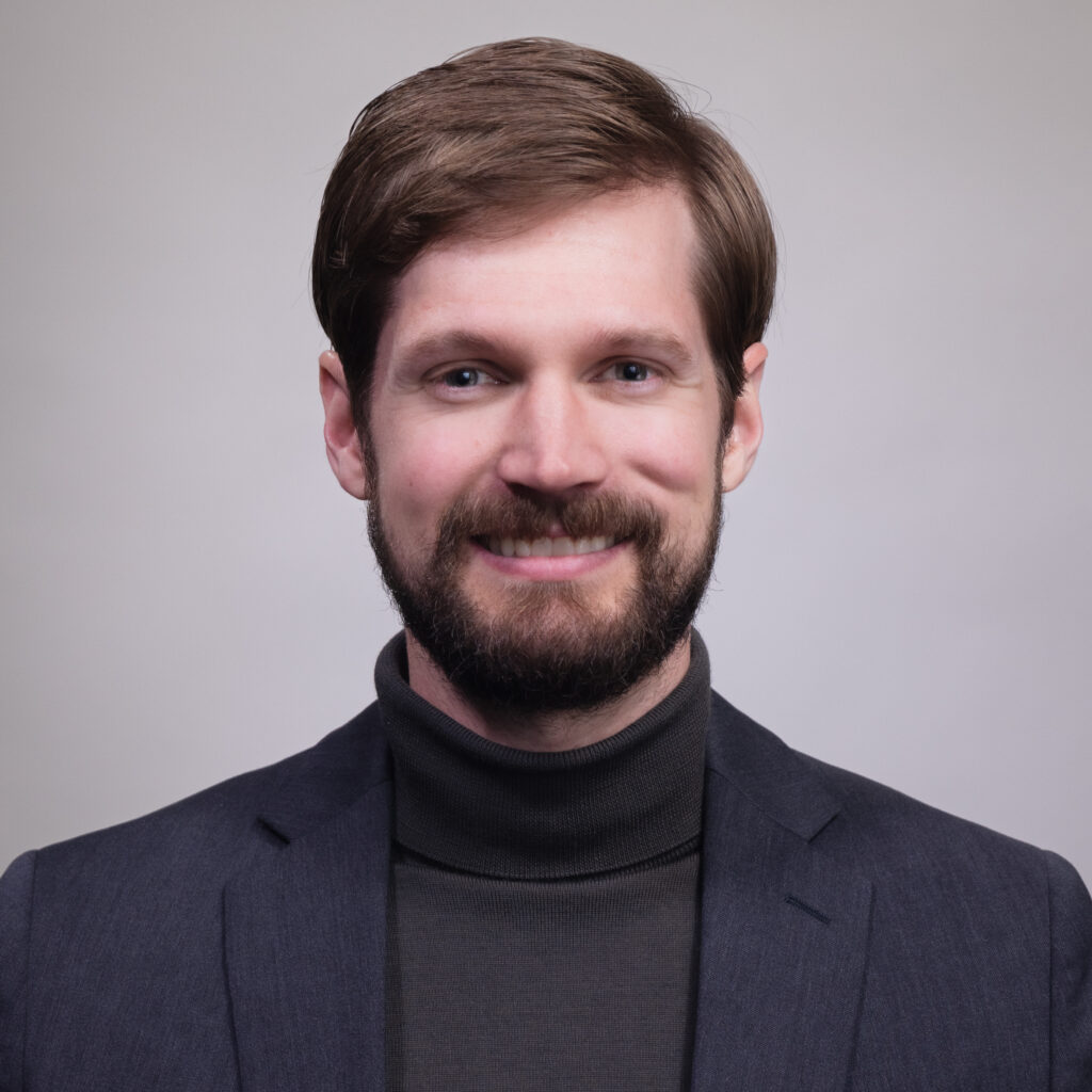 Joseph Lambson smiles in a black jacket.